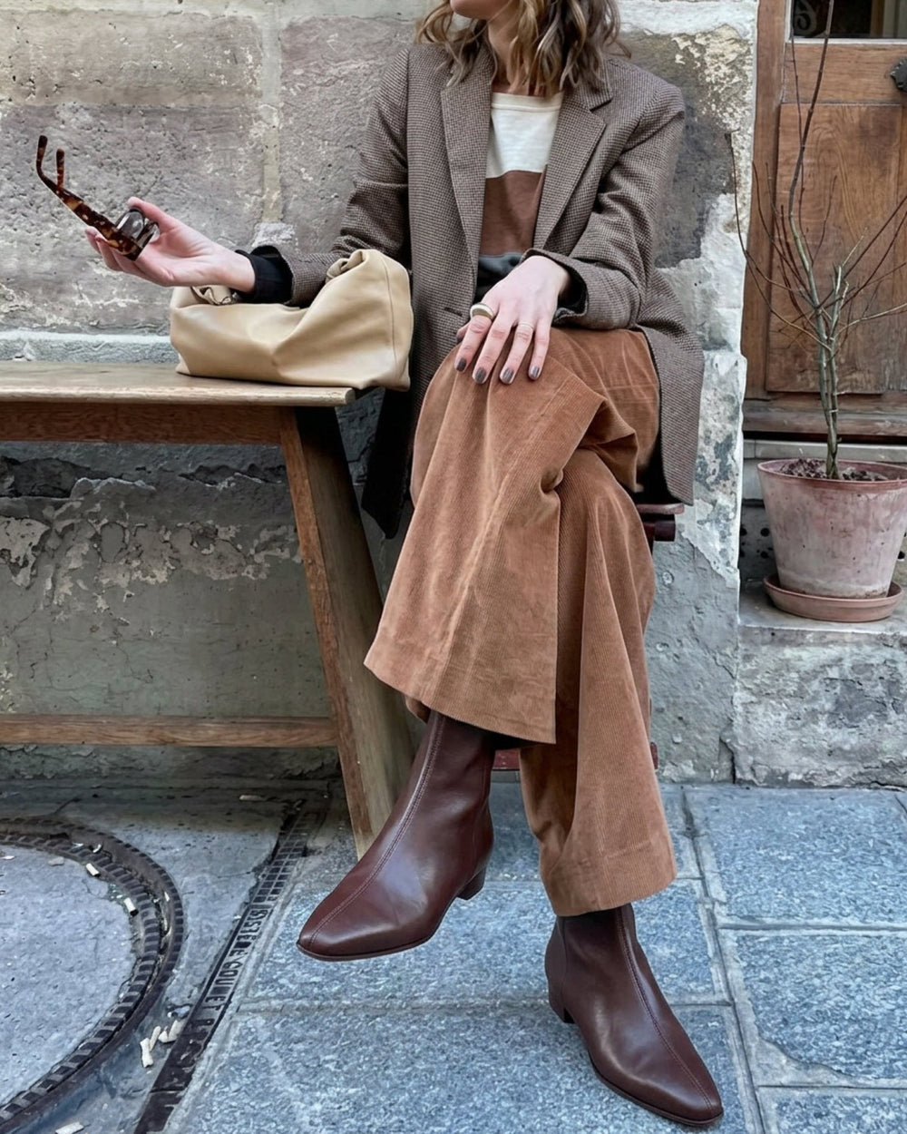 Rema Ankle Bootie in dark chocolate with a sharp tapered toe peeking out from under wide-leg jeans