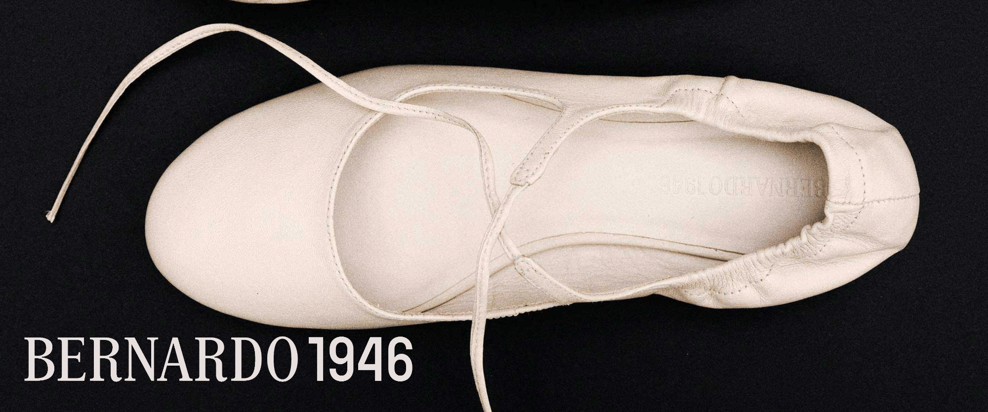 White Bernardo 1946 ballet shoe with laces on a black background
