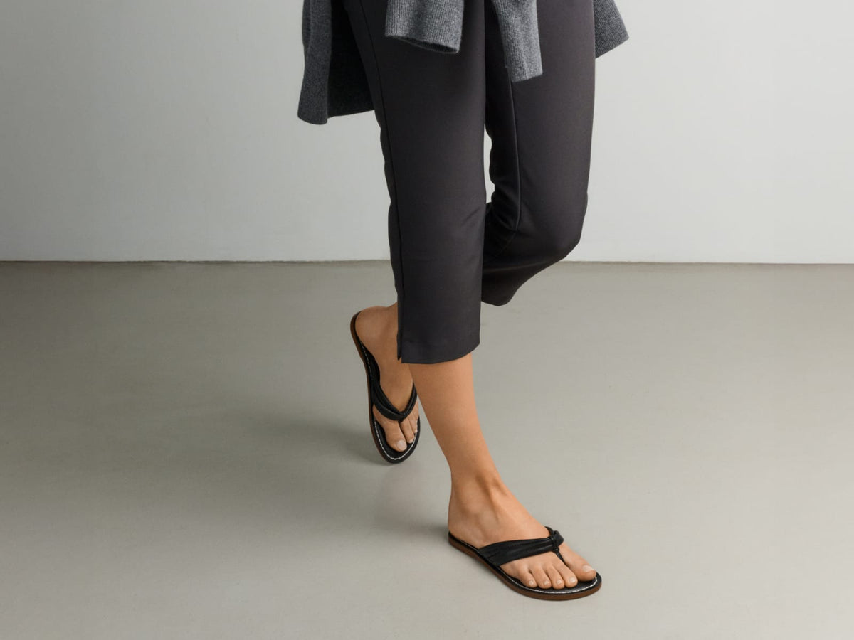 Woman wearing the black Miami Thong Sandal with cropped black trousers